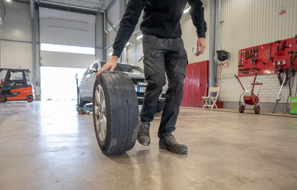 En man rullar ett bildäck över ett blankt golv.