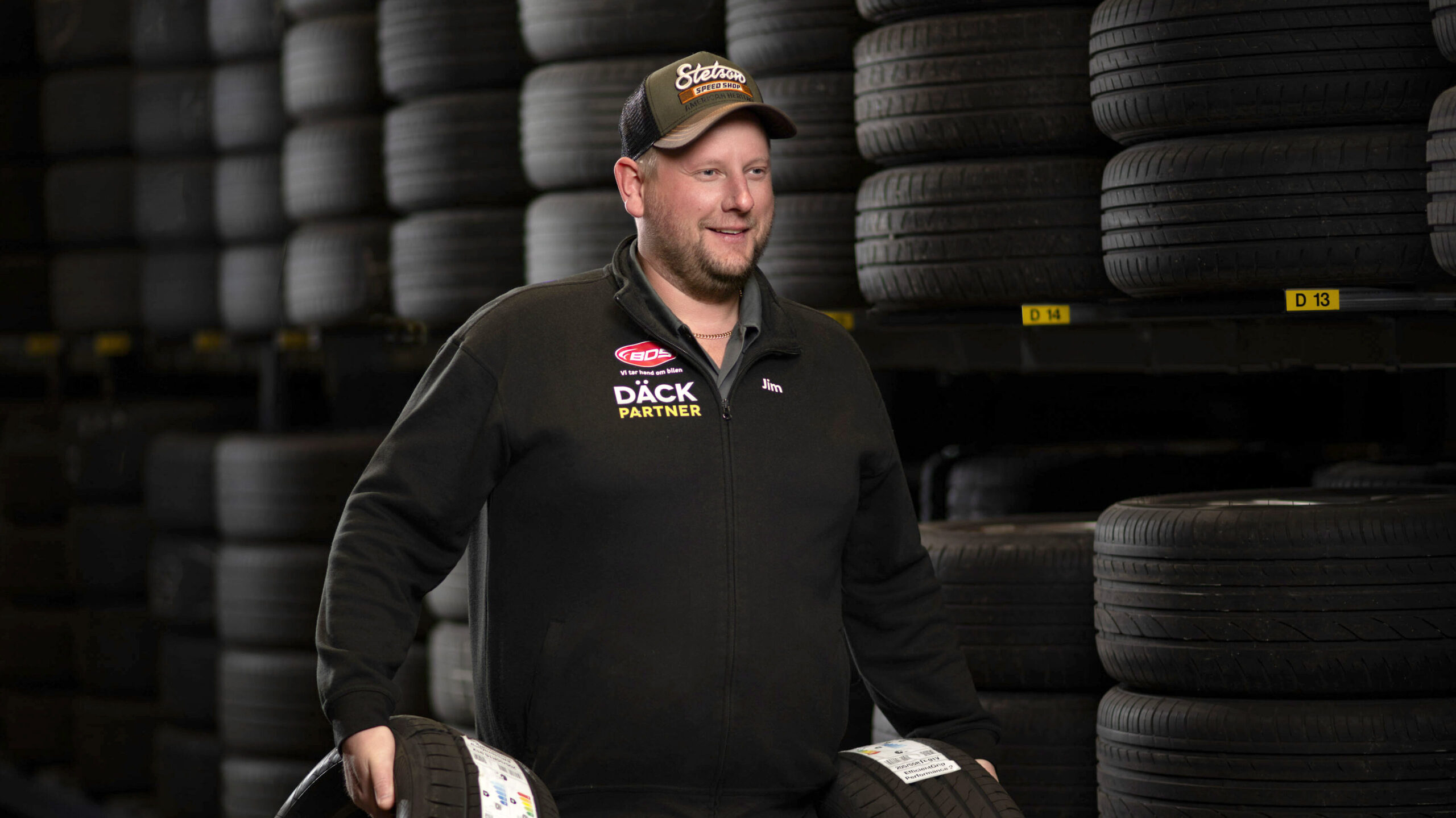 bilmekaniker bär på nya däck i däckhotellet hos Hedemora Däck & Bilservice